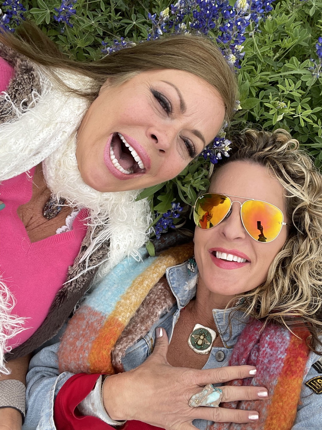 Two women laughing among Texas bluebonnets, both wearing turquoise pieces